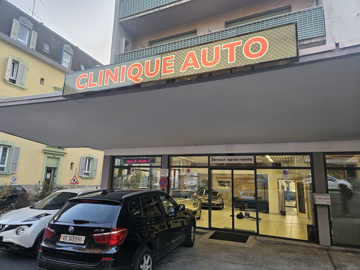 La façade de Clinique Auto à Renens, avec son enseigne lumineuse